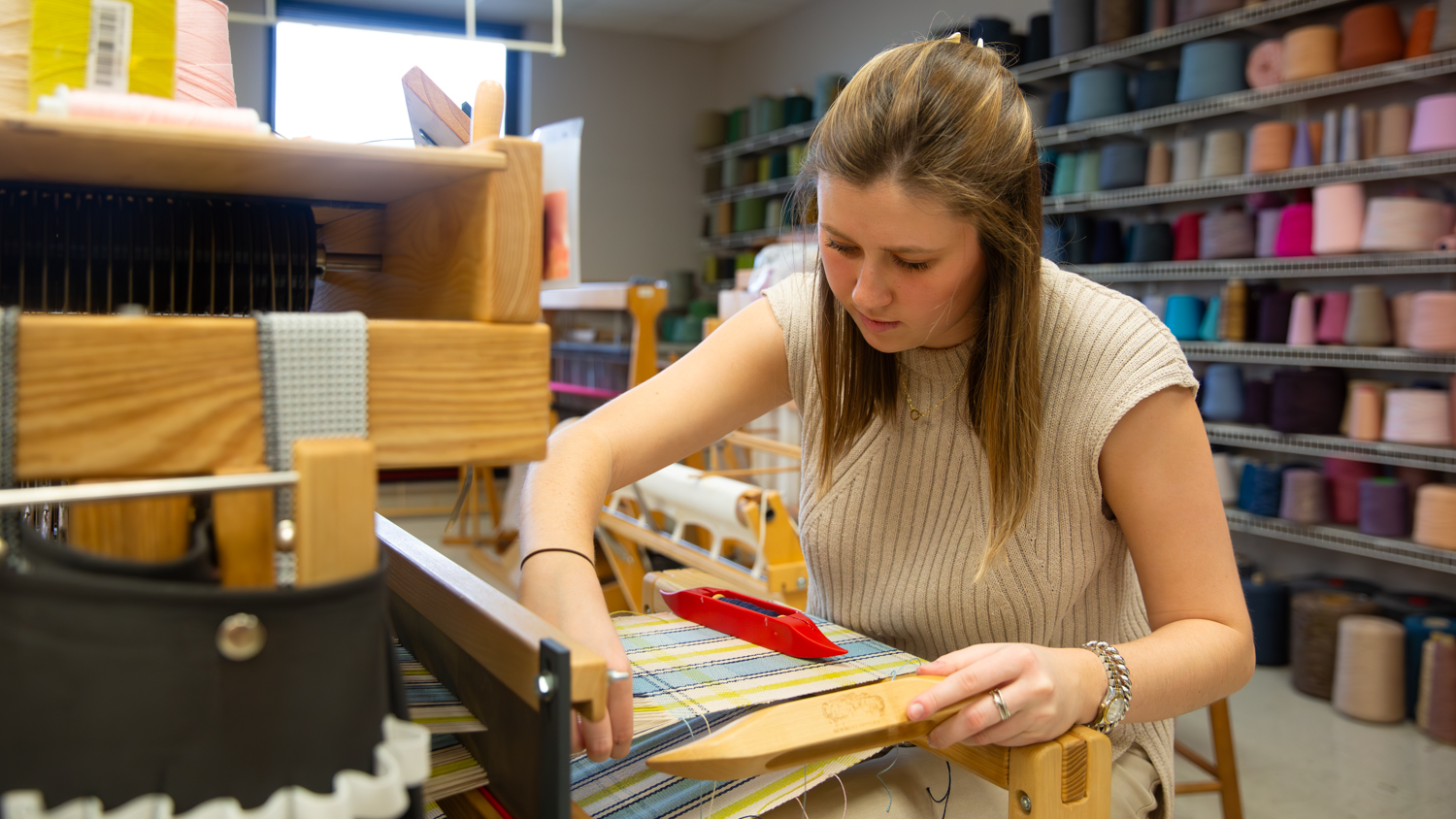 Mary Mac Lyons works on a loom in a weaving lab.